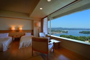 松岛町松岛大观庄度假酒店的酒店客房设有两张床和大窗户。