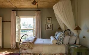 埃尔金Vredenhof Farm Cottage的一间卧室设有天蓬床和窗户。