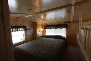 MiltonBlackhawk RV Campground Loft Cabin 11的小木屋内的一张大床,设有两个窗户