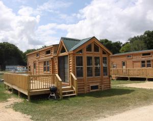 MiltonBlackhawk RV Campground Loft Cabin 11的大型小木屋设有门廊和甲板