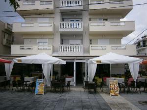 奥林匹亚基·阿克蒂约安娜酒店 的建筑物前的两把白色遮阳伞