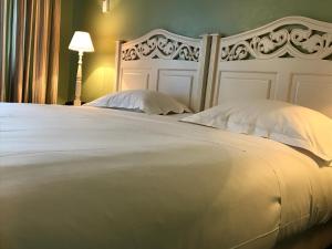 戛纳菲斯蒂瓦酒店的一张带两个枕头和一盏灯的大型白色床