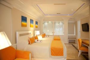 圣斐利-银港Cofresi Palm Beach & Spa Resort - All Inclusive的卧室配有带橙色枕头的大型白色床