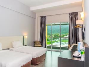 怡保MH Sentral Hotel Sg Siput的酒店客房设有两张床、一张书桌和一个窗户。
