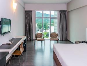 怡保MH Sentral Hotel Sg Siput的酒店客房,配有一张床、一张桌子和椅子