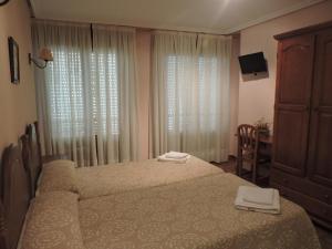 纳瓦雷特Hostal Villa de Navarrete的一间卧室配有两张床、一个梳妆台和窗帘