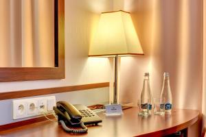 格但斯克琥珀酒店 的电话和带瓶子的书桌上的台灯