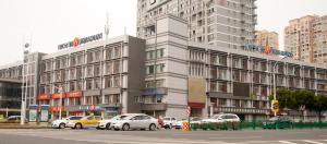 苏州锦江之星品尚吴江同里云梨桥酒店的一座大型建筑,前面有汽车停放