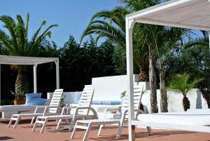 加拉托内坎皮拉提尼农家公寓式酒店的庭院里摆放着一组白色的椅子和遮阳伞