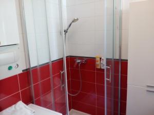萨格勒布加森公寓的浴室铺有红色和白色瓷砖,设有淋浴。