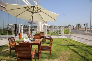 阿尔卡夫奇Raoum Inn Khafji Corniche的草上带雨伞的桌椅