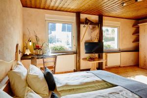Wildewiese斯坦伯格瓦尔德怀塞自然酒店的一间卧室设有一张床、一台电视和两个窗户。