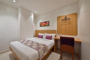 孟买Hotel Leafio-Near Airport的酒店客房配有一张床、一张书桌和一张四柱床