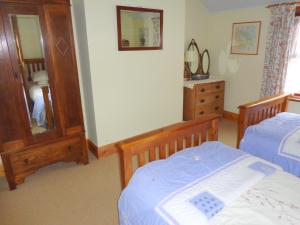 SulbyBallacowell Cottage的一间卧室配有两张床、镜子和梳妆台