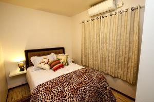 格拉玛多Apartamento Aconchegante Na Serra的一间卧室配有一张带猎豹毛毯的床