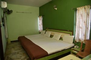 库姆巴科纳姆Hotel Chela的一间卧室设有一张带绿色墙壁的大床