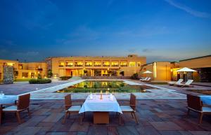 布什格尔Dera Masuda Luxury Resort的配有桌椅和游泳池的酒店