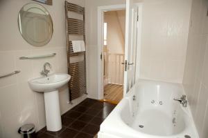 卡斯尔敦贝尔Berehaven Lodge的浴室设有白色浴缸、水槽和镜子