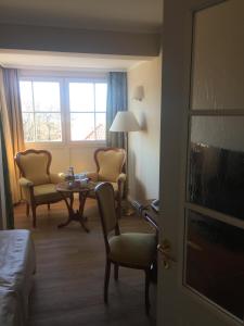 格拉尔-米里茨Strandhotel Deichgraf Graal-Müritz的酒店客房带一张床、一张桌子和椅子