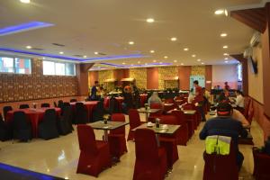 邦加槟港Puncak Budget Hotel的一间设有桌椅的餐厅,房间里有人