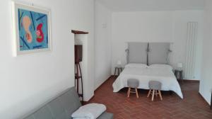斯佩洛Podere Le Volte degli Angeli的卧室配有白色的床和2张凳子