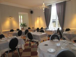 图兰的圣莫尔白马之家酒店的餐厅设有白色的桌椅和窗户。