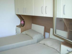 维耶斯泰Villa Grazia的配有白色橱柜的小客房内的两张床