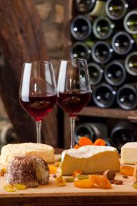 热夫雷尚贝尔坦艺术及风土条件之家酒店的切盘上放两杯葡萄酒和奶酪