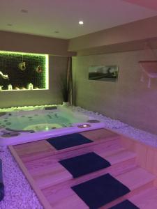 Tillé桑斯奥克斯5号酒店的紫色照明的客房内的按摩浴缸