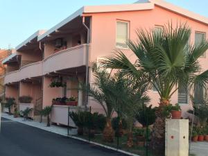 乌尔齐尼Familien Apartment Zeno的前面有棕榈树的粉红色建筑