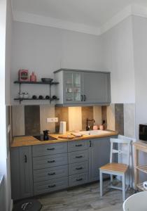 维斯普雷姆Óváros Apartman的厨房配有灰色橱柜和白色椅子