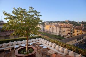 佛罗伦萨Hotel Continentale - Lungarno Collection的大楼内的阳台配有椅子和一棵树