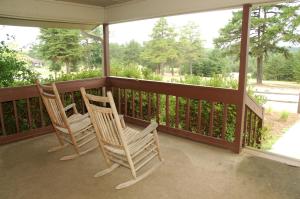 Fair PlayCarolina Landing Camping Resort Cabin 14的门廊上设有两张摇椅,享有美景