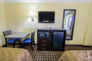 棕榈滩花园亚美利加汽车旅馆的酒店客房设有桌子、电视、桌子和镜子