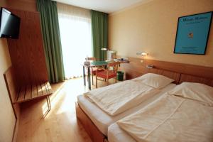 吕嫩泊斯鲁尔城市友好酒店的一间卧室配有两张床、一张桌子和一台电视。