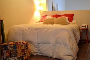坦迪尔Loft Urbano的一间卧室配有一张大床,配有白色床单和红色枕头
