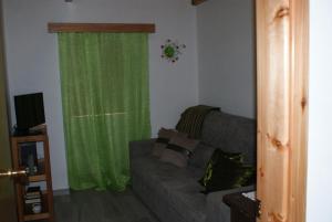 UrzelinaCantinho do mar的带沙发和绿色窗帘的客厅