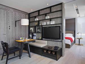 香港哲維斯酒店的一间卧室配有一张床、一台电视和一张桌子