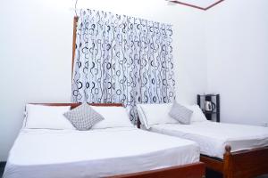 波隆纳鲁沃Livinginn Polonnaruwa的一间卧室配有两张床和窗帘