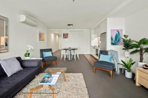 墨尔本墨尔本港海滩公寓的客厅配有沙发、椅子和桌子