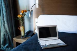 马德里TaCH Madrid Airport的坐在酒店房间床上的笔记本电脑