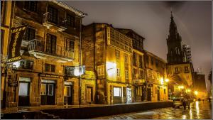 圣地亚哥－德孔波斯特拉Oxford Suites Santiago de Compostela的一条老城街道,晚上有教堂
