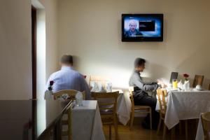 伦敦The Brent Hotel - London - Wembley的两人坐在餐厅里,墙上有电视