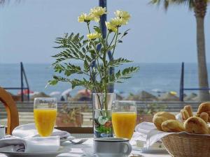 拉安蒂拉Hotel Marlin Antilla Playa的一张桌子,上面放着两杯橙汁和花瓶