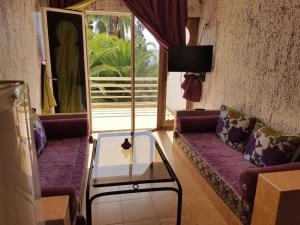 阿加迪尔Residence Tafat的客厅配有紫色沙发和玻璃桌