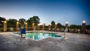 Madill森德贝斯套房贝斯特韦斯特PLUS酒店的庭院内带蓝色椅子的游泳池