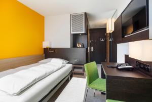 苏黎世祖利法斯班德酒店的一间卧室配有一张床、一张书桌和一台电视