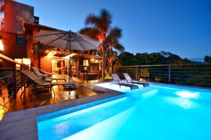 普腊亚罗萨Villa Gardena Suites的房屋旁的游泳池配有椅子和遮阳伞