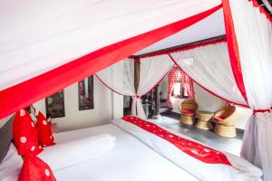 武吉拉旺武吉拉旺生态住宿加早餐旅馆的卧室配有红色和白色的天蓬床