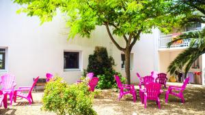雷岛林滩Village Vacances Passion Ré La Blanche的树下一组粉红色的椅子和桌子